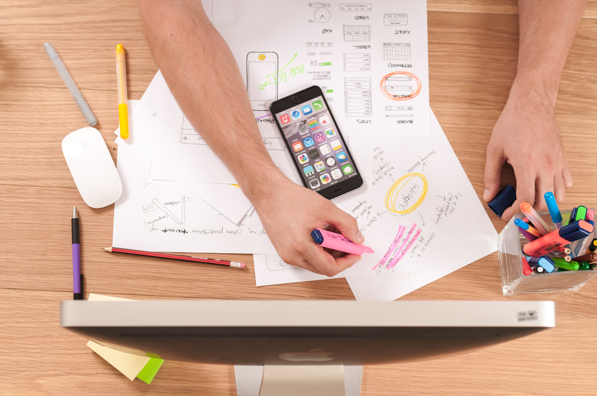 Website wireframe sketches on a desk with phone and pens